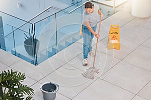 Cleaning service, office building or woman mopping floor with warning sign for job safety compliance. Bucket, bacteria