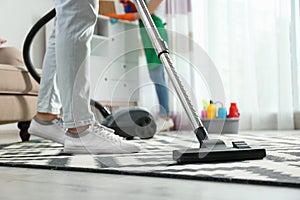 Cleaning service professional vacuuming carpet indoors