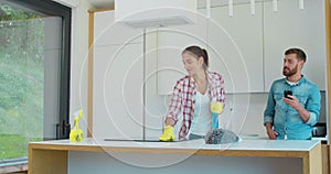 Cleaning service team at work in kitchen.Man using smartphone.