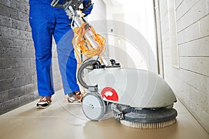 Worker with machine cleaning floor in residence hall