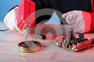 Cleaning the soldering iron tip in rosin on the table by a person