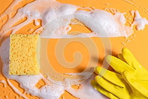 Cleaning sponge with foam and rubber glove on a bright yellow background. household chores and cleaning concept