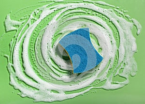 cleaning sponge wiping foam soap suds on blue background, household washing concept