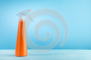 Cleaning Spray Bottle of detergent. Concept of spring cleaning home. Plastic Orange bottle on blue background with copy space