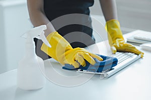 Cleaning staff wiping down office equipment, Wipe the keyboard clean with a towel and disinfectant. Wear rubber gloves when