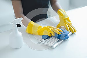 Cleaning staff wiping down office equipment, Wipe the keyboard clean with a towel and disinfectant. Wear rubber gloves when