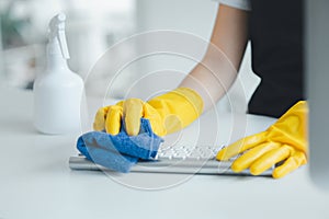 Cleaning staff wiping down office equipment, Wipe the keyboard clean with a towel and disinfectant. Wear rubber gloves when