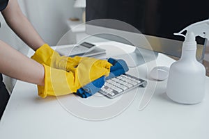 Cleaning staff wiping down office equipment, Wipe the keyboard clean with a towel and disinfectant. Wear rubber gloves when