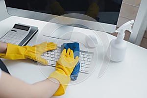 Cleaning staff wiping down office equipment, Wipe the keyboard clean with a towel and disinfectant. Wear rubber gloves when