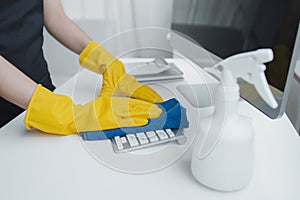 Cleaning staff wiping down office equipment, Wipe the keyboard clean with a towel and disinfectant. Wear rubber gloves when