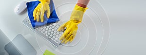 Cleaning staff wiping down office equipment, Wipe the keyboard clean with a towel and sanitizer, Wear rubber gloves when working