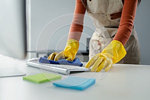 Cleaning staff wiping down office equipment, Wipe the keyboard clean with a towel and sanitizer, Wear rubber gloves when working