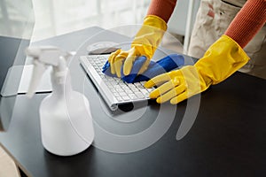 Cleaning staff wiping down office equipment, Wipe the keyboard clean with a towel and sanitizer, Wear rubber gloves when working