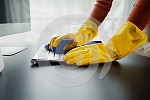 Cleaning staff wiping down office equipment, Wipe the keyboard clean with a towel and sanitizer, Wear rubber gloves when working