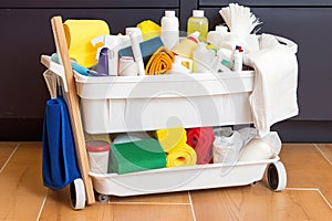 cleaning supplies bin overflowing with rollers, mops, sponges and towels