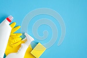 Cleaning supplies on blue background. Top view cleaner spray bottle, rag, yellow sponge, detergent, rubber gloves. House cleaning