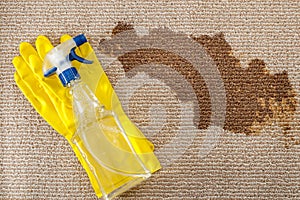 Cleaning supplies and carpet sanitizing concept with a pair of yellow rubber gloves and a bottle of carpet cleaner with a spray