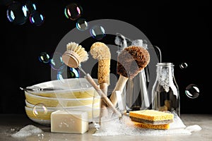 Cleaning supplies for dish washing and soap bubbles on black background