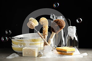 Cleaning supplies for dish washing and soap bubbles on black background