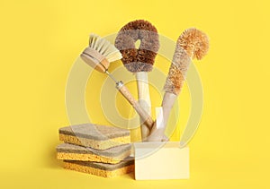 Cleaning supplies for dish washing on yellow background