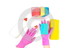 Cleaning supplies isolated on white: a small shopping basket with dishwashing sponges, yellow cleaning cloth, two plastic bottles