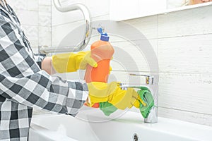 Cleaning Tap. cleaning bathroom sink and faucet with detergent in bathroom. Man doing chores cleaning bathroom at home. cleaning