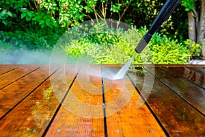 Cleaning the terrace with a pressure washer - high-pressure cleaner on the wooden surface of the terrace - very shallow depth of