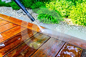 Cleaning the terrace with a pressure washer - high-pressure cleaner on the wooden surface of the terrace - very shallow depth of