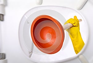 Cleaning the toilet with a plunger. Bathroom toilet plunger suction in a hand gets in the toilet.