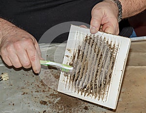 Cleaning a very dirty kitchen exhaust fan from dirt with a brush. A man cleans the parts of a fan with a brush