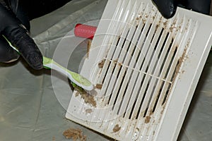 Cleaning a very dirty kitchen exhaust fan from dirt with a brush. A man cleans the parts of a fan with a brush