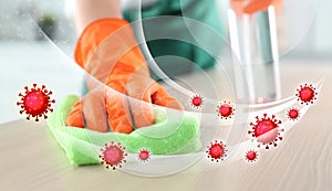 Cleaning vs viruses. Woman washing table with sponge and disinfecting photo