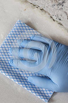 Cleaning white granite countertop worktop with a cloth. Housework chores concept