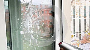 Cleaning window pane with spray detergent with lots of soap suds. The concept of cleanliness, cleaning, spring