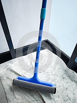 Cleaning windows with a blue squeegee during spring cleaning