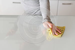 Cleaning wipe with a cloth in the hands of woman kitchen table.  Housekeeping service. The concept of disinfection. Protection