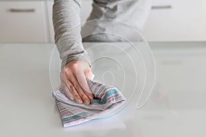 Cleaning wipe with a cloth in the hands of woman kitchen table.  Housekeeping service. The concept of disinfection. Protection