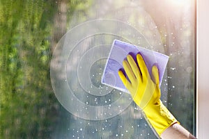 Cleaning woman hand wipes the window from the cleaning agent with a rag