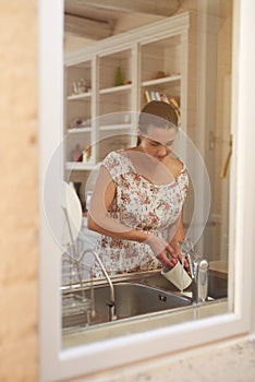 Cleaning, woman and washing dishes in kitchen in house, apartment and home for housekeeping and cleanliness. Cup, water