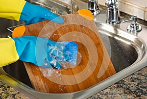 Cleaning Wooden Cutting board inside of Kitchen Sink with sponge