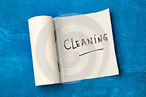 Cleaning word write on a paper kitchen napkin roll on a blue background