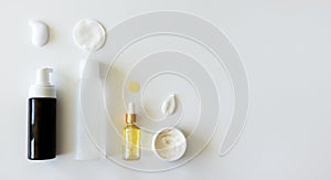 Cleanser foam, tonic and cotton pad, oil serum essence drop and moisturizer smear. Mockup bottles on white background. Beauty