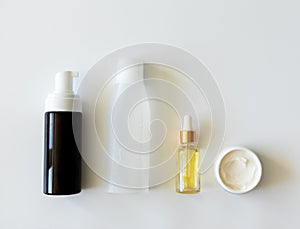 Cleanser foam, tonic, serum essence and moisturizer mockup bottles on white background. Step facial skincare, above