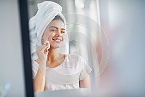 Cleansing her skin to reveal her natural beauty. a beautiful young woman cleaning her face with cotton wool in the