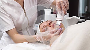 Cleansing the skin of a woman's face with ultrasonic cavitation peeling.