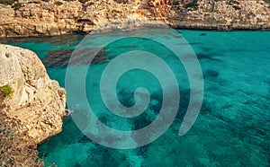 Clear blue green sea water, rocky cliffs around - nice sunny day at Ansa de s`Estri, Mallorca