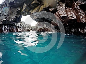 Clear blue ocean water in a lava rock cavern