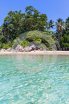 Clear blue sea and beach with palm trees. View from the sea to the Thailand beach, large stones on the shore and clean sand