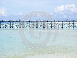 Clear blue sea, sky, white clouds and wooden bridge