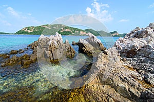 Clear blue sea water with stone and big mountain.